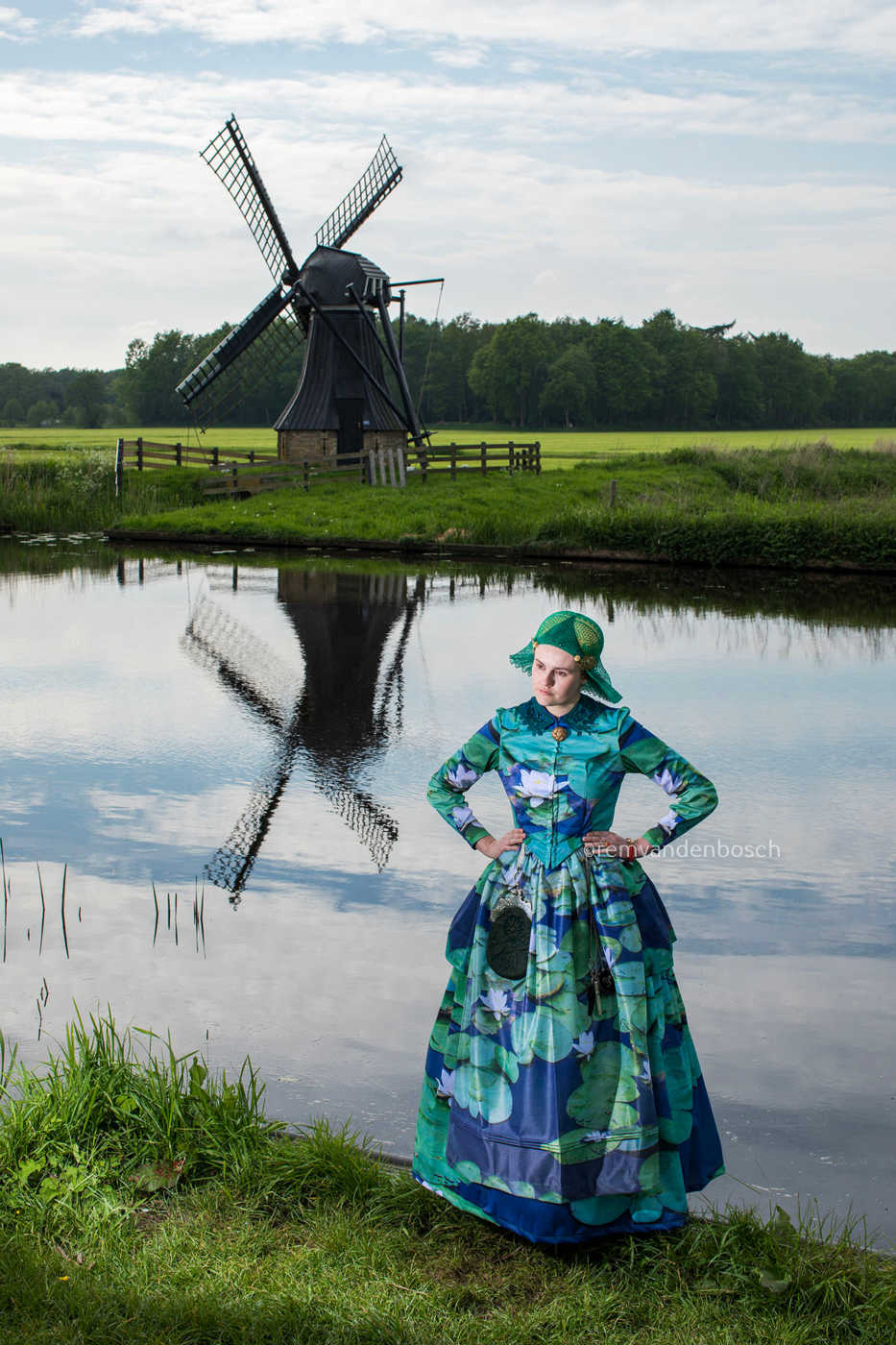 Portret van Linde in moderne groene Friese dracht met waterlelieprint aan het water met houten molen. Tijdloze Nederlandse wandkunst.