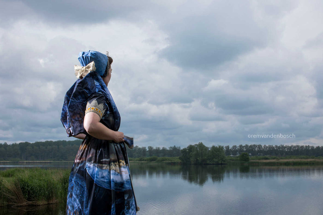 Liggend rugaanzicht in moderne Axelse dracht in blauwtinten aan het water met de watertoren van Axel , kunstfotografie door Rem van den Bosch