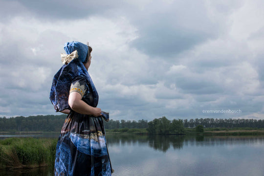 Liggend rugaanzicht in moderne Axelse dracht in blauwtinten aan het water met de watertoren van Axel , kunstfotografie door Rem van den Bosch
