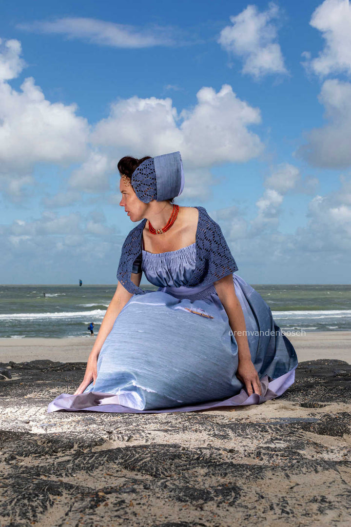 Ana in moderne Walcherse zeedracht op de dijk bij Westkapelle met de zee op de achtergrond, Zeeuwse wandkunst, Rem van den Bosch 
