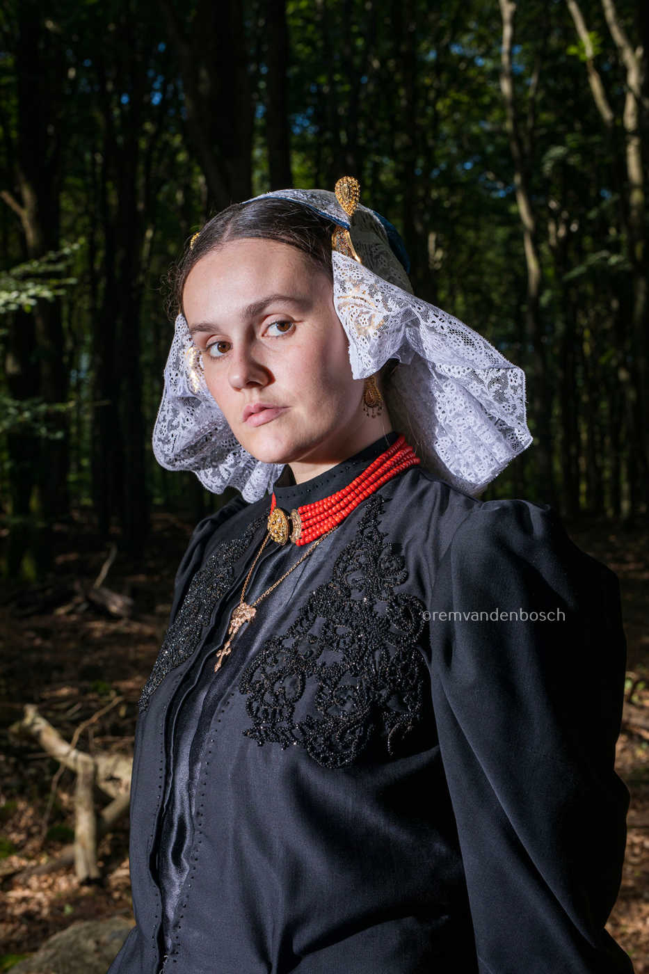 Portret van Linde in de dracht van Gooi- en Eemland met muts en sieraden tegen een donkere bosachtergrond