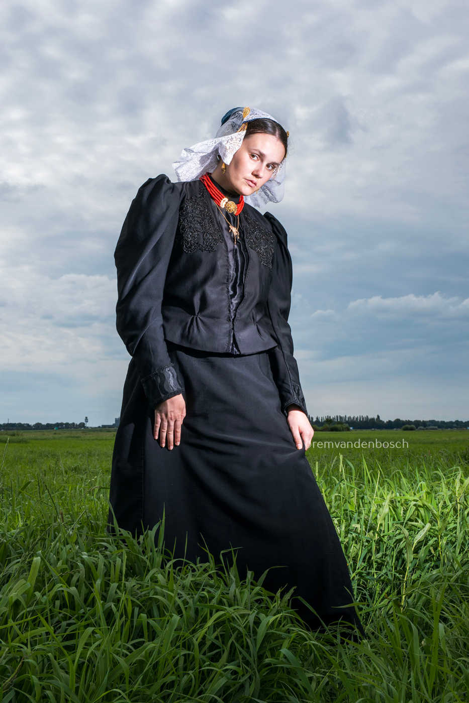 Linde in traditionele dracht van Gooi- en Eemland, staand in een veld en de kijker aankijkend. Fotografie Rem van den Bosch 
