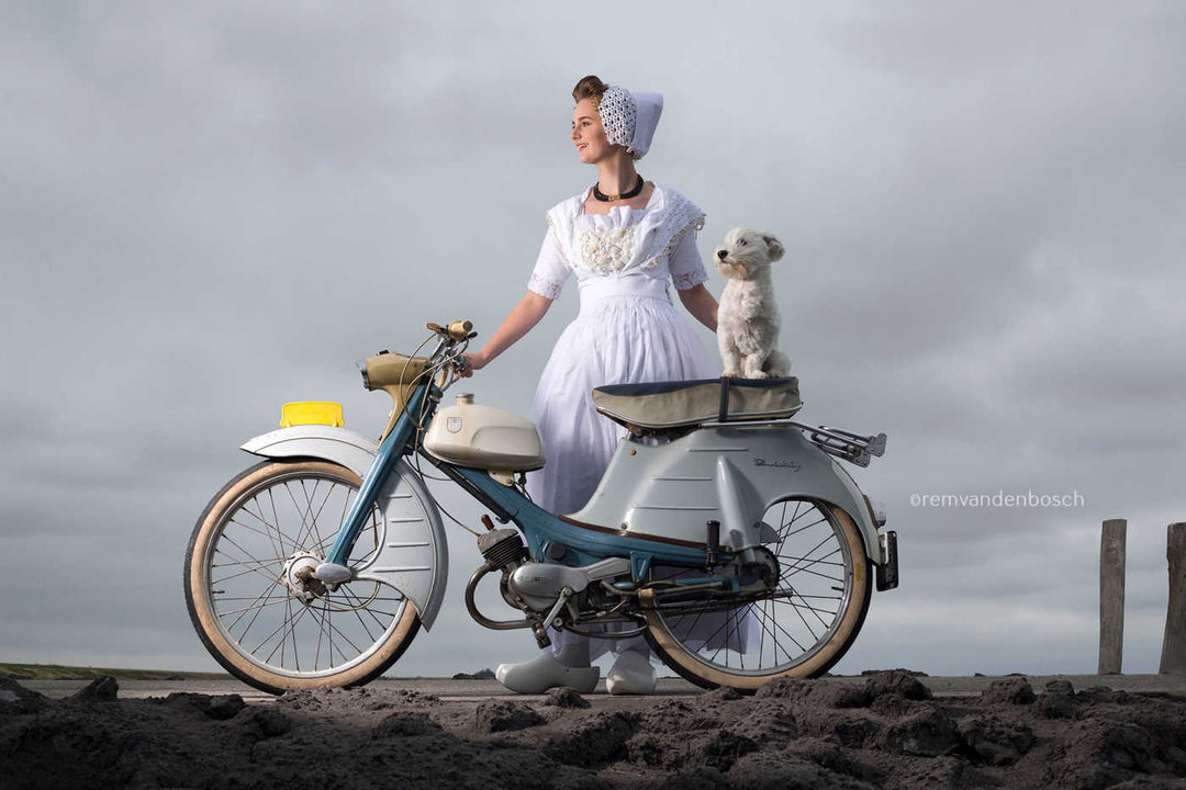 Liggend fotobeeld van Yael in spierwitte moderne Walcherse dracht met brommer en wit hondje , Zeeuwse wandkunst