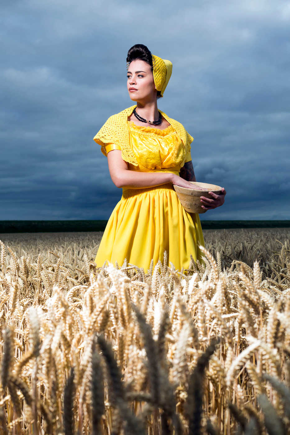 Staand portret van Daisy in moderne gele Walcherse dracht in een veld vol rijpe tarwe , Zeeuwse wandkunst