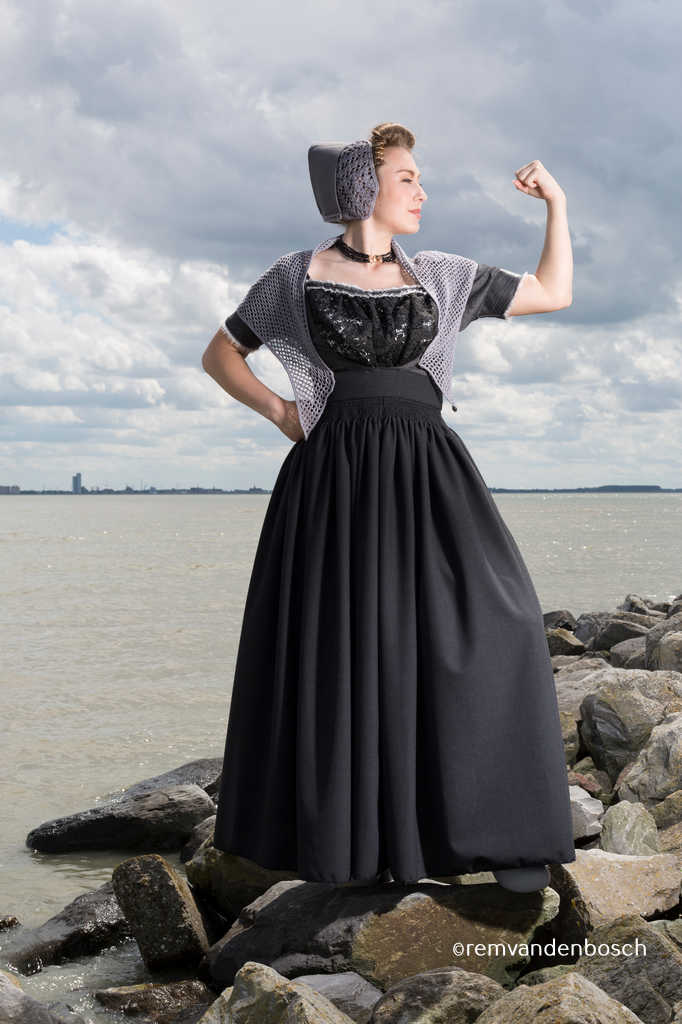 Rebecca in grijze moderne Walcherse dracht met Yes we can-pose op de Zeeuwse dijk, Zeeuwse wandkunst