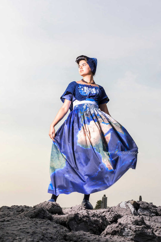 Esmee in moderne Walcherse werelddracht, staand op de dijk. Eigentijdse Zeeuwse wandkunst 