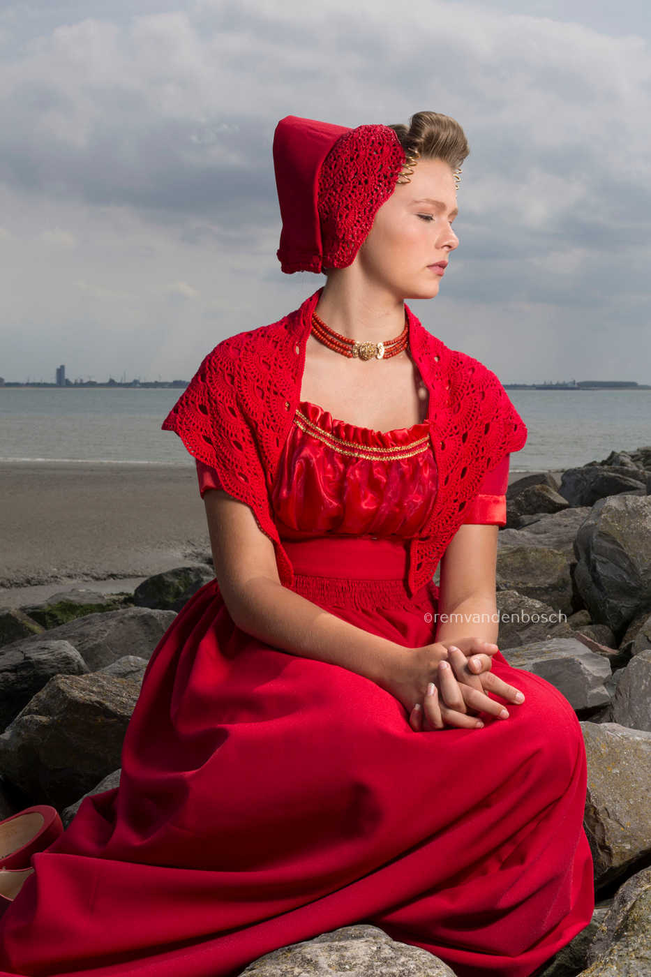 Phoebe in moderne rode Walcherse dracht zittend op de Zeeuwse dijk, ingetogen Zeeuwse wandkunst
