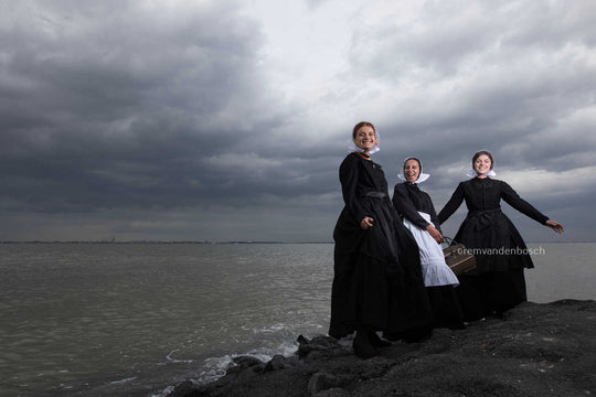 Liggend portret van Charlotte, Janis en Ilyana in Cadzandse dracht aan zee, stralend en vrolijk, kunstfotografie door Rem van den Bosch
