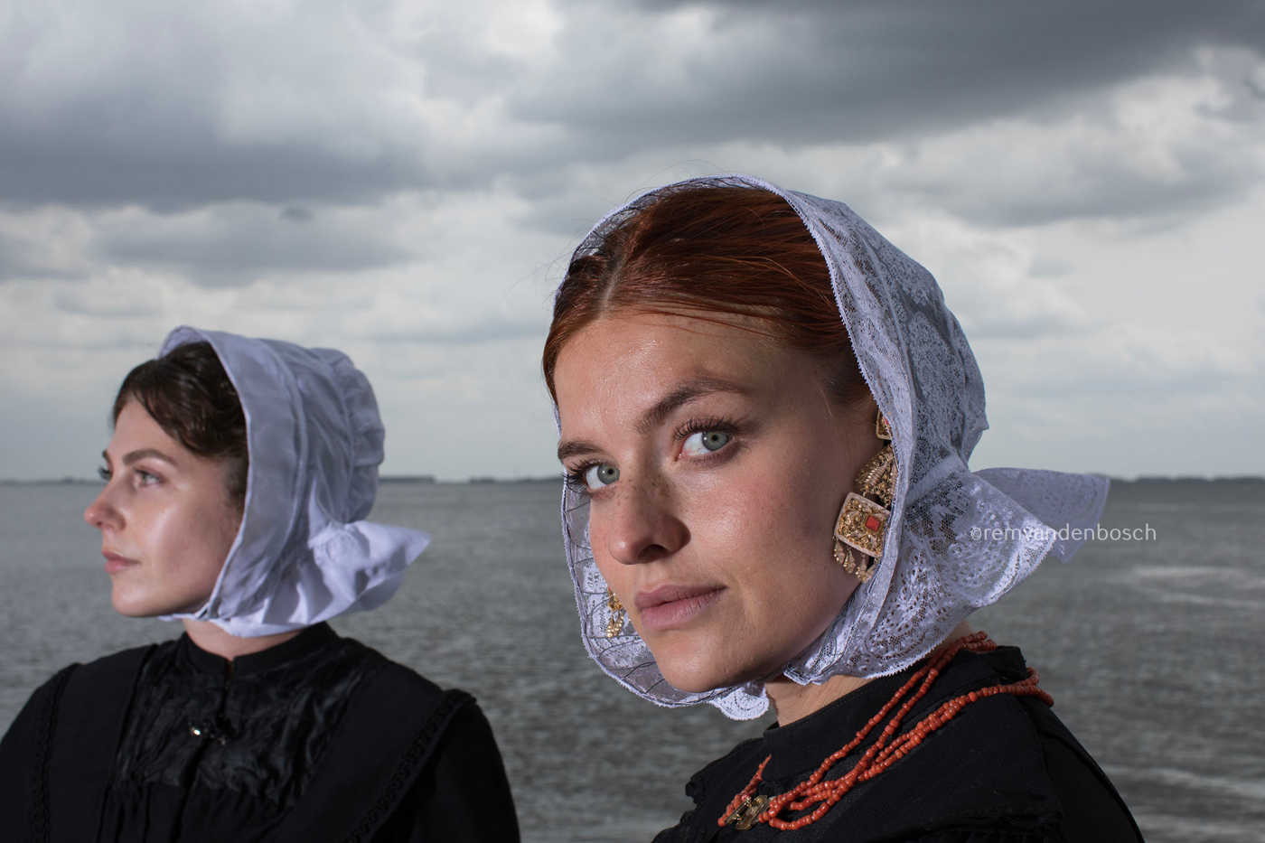 Liggend portret van Charlotte en Janis in Cadzandse dracht aan zee, kunstfotografie door Rem van den Bosch