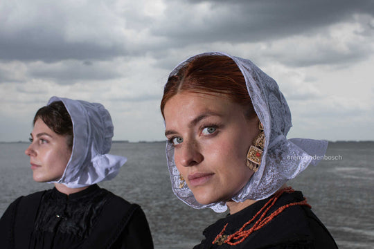 Liggend portret van Charlotte en Janis in Cadzandse dracht aan zee, kunstfotografie door Rem van den Bosch