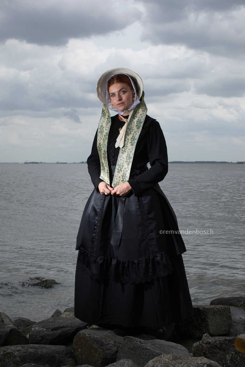 Staand portret van Charlotte in zondagse dracht met zee,  kunstfotografie door Rem van den Bosch