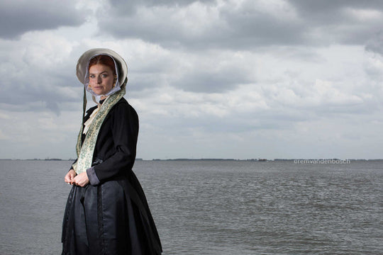 Liggend portret van Charlotte in zondagse dracht met zee, kunstfotografie door Rem van den Bosch