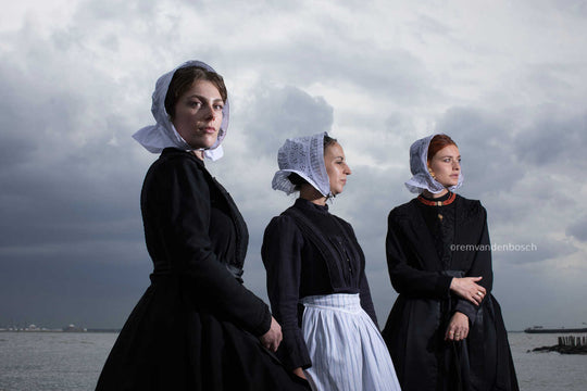 Liggend groepsportret van Charlotte, Janis en Ilyana in Cadzandse dracht aan zee, kunstfotografie door Rem van den Bosch