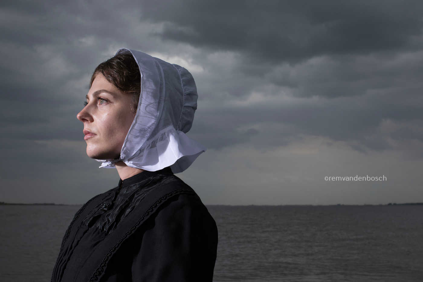 Liggend portret van Janis in Cadzandse dracht met zee , kunstfotografie door Rem van den Bosch