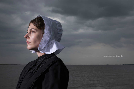 Liggend portret van Janis in Cadzandse dracht met zee , kunstfotografie door Rem van den Bosch