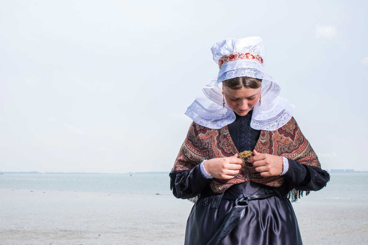Hanna in traditionele Hulster dracht aan zee, liggend portret met sieraden – kunstfotografie door Rem van den Bosch