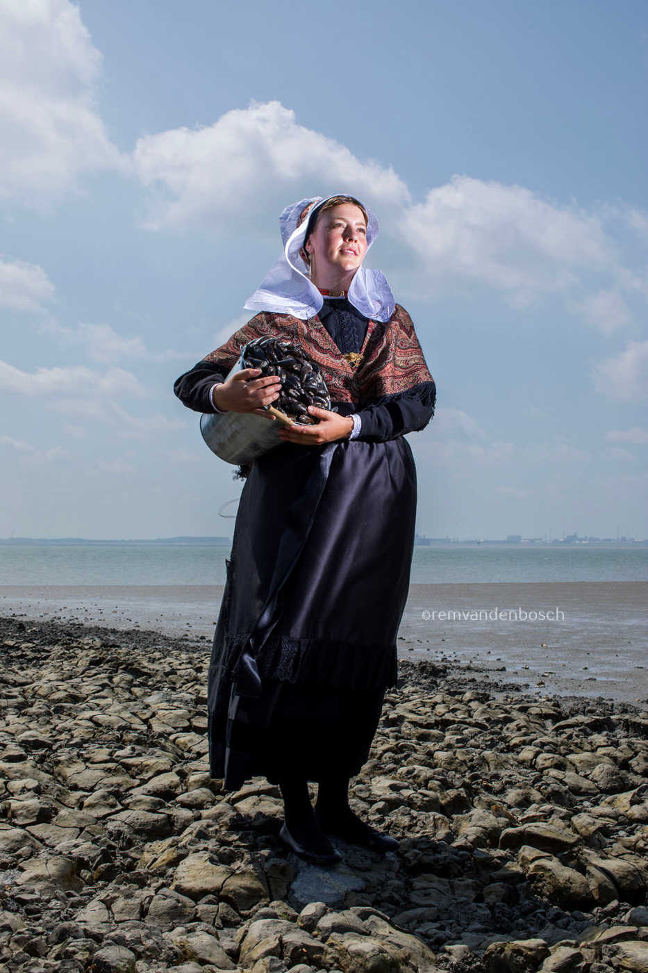 Hanna in traditionele Hulster dracht met een emmer mosselen – kunstfotografie door Rem van den Bosch
