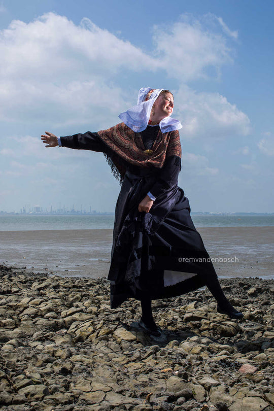 Lachende Hanna in traditionele Hulster dracht met open armen op het strand – kunstfotografie door Rem van den Bosch