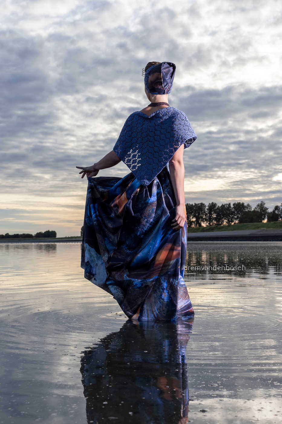 Achteraanzicht van Iris in moderne Walcherse mosseldracht in ondiep zeewater tijdens een zomerse avond 