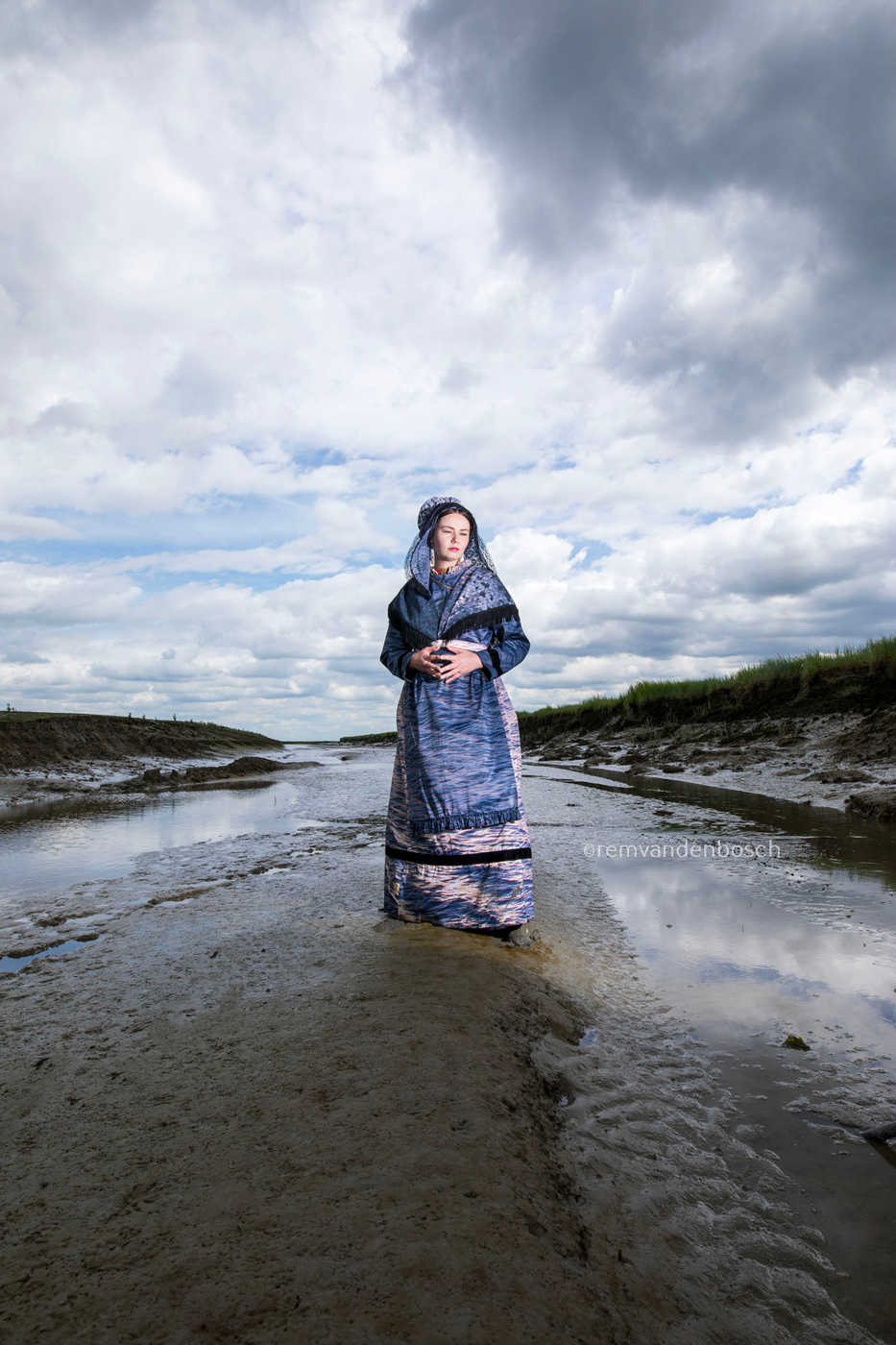 Lois in moderne Hulster dracht in blauw-grijze tinten in Saeftinghe, kunstfotografie door Rem van den Bosch