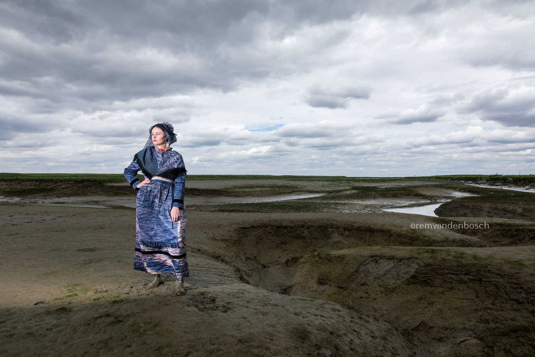 Lois in moderne Hulster dracht in blauw-grijze tinten in Saeftinghe, kunstfotografie door Rem van den Bosch