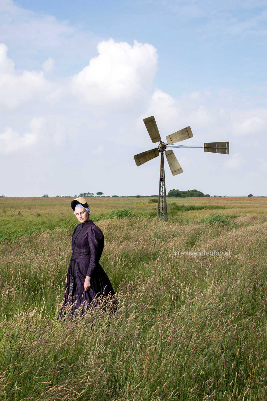 Linde in de traditionele dracht van Wieringen in een  veld met windrad, fotografie Rem van den Bosch 