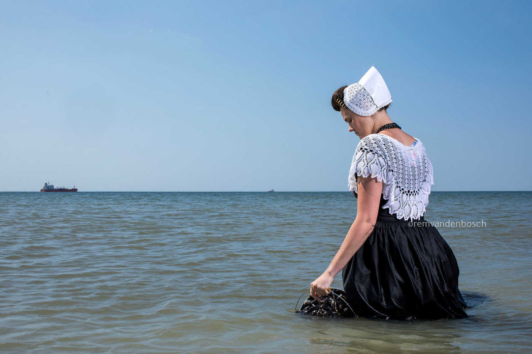 Zeeuwse boerin tot haar helft in de zee met een emmer mosselen. Foto Rem van Den Bosch 