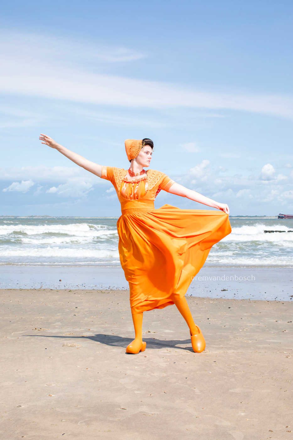 Linde in moderne oranje Walcherse dracht op het strand met de zee op de achtergrond, Zeeuwse wandkunst