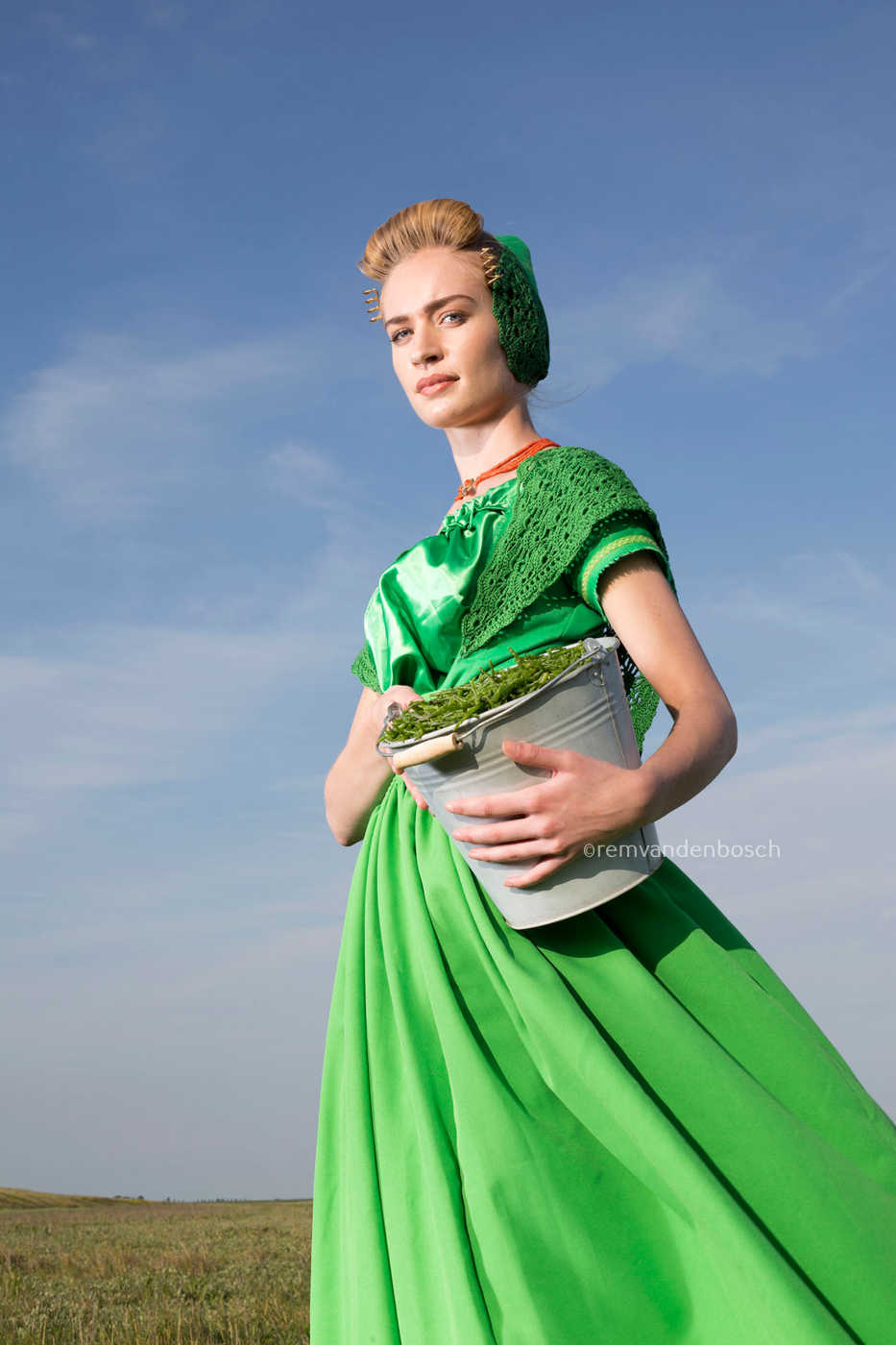 Dana in moderne groene Walcherse dracht met een emmer zeekraal, staand in de slikken en schorren , Zeeuwse wandkunst