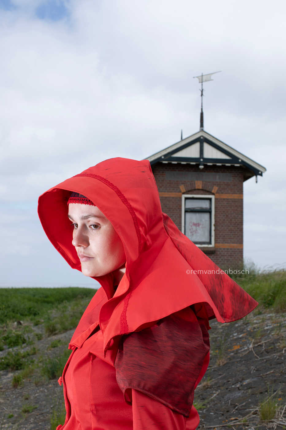 Linde in moderne rode Wieringse rouwdracht, staand op de dijk, Nederlandse wandkunst, fotografie Rem van den Bosch 