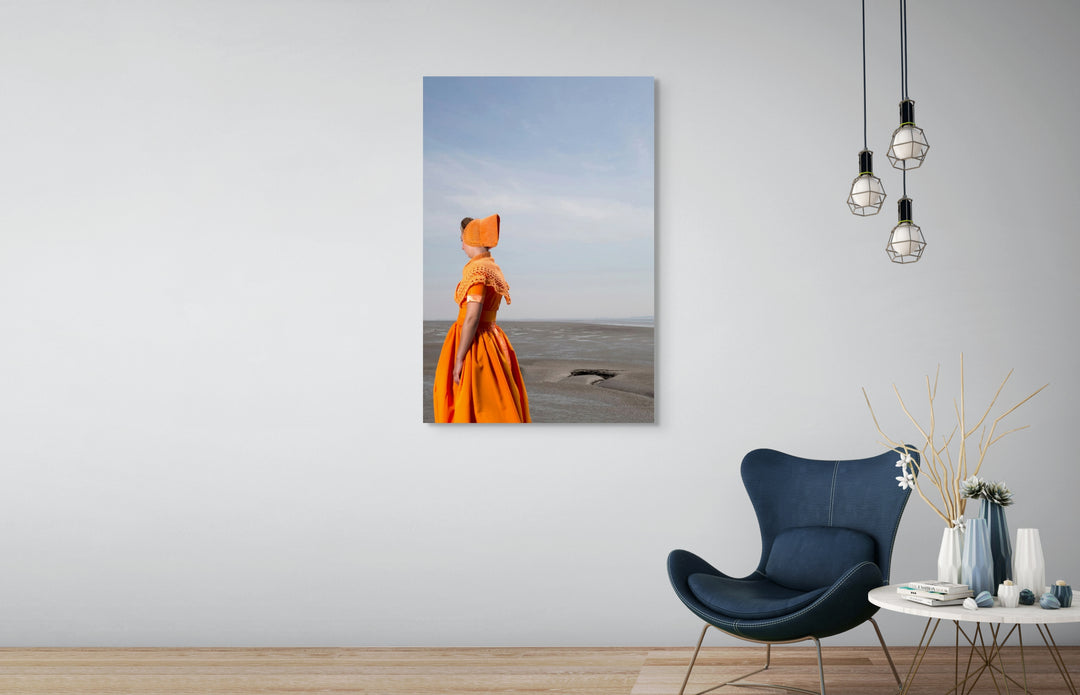 Muurdecoratie, Rem van Den Bosch, fotografie, Ruby in moderne oranje Walcherse dracht in de slikken aan zee – Zeeuwse wandkunst